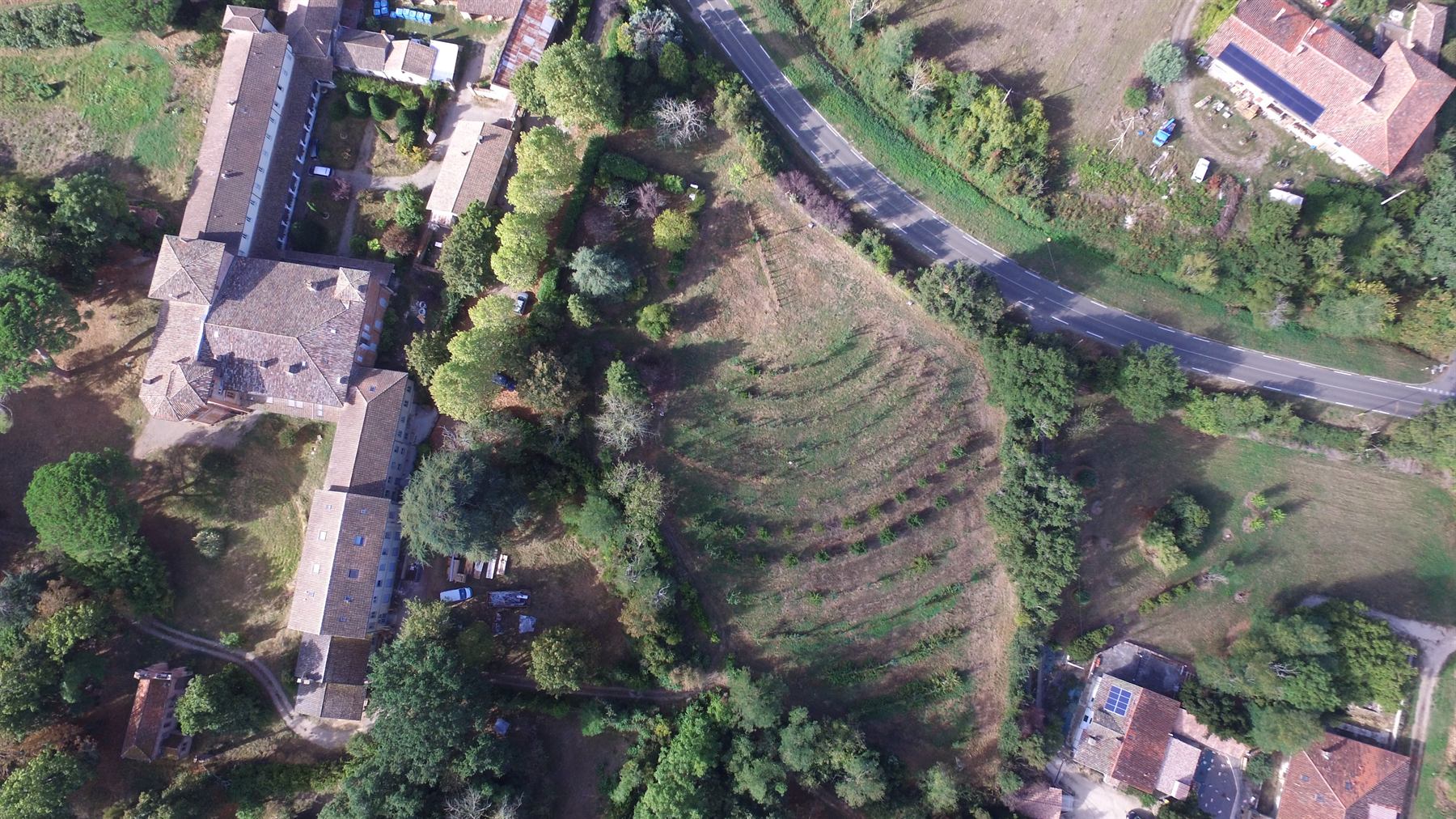 The abbey ranges and the orchard seen together from the air, with the village beyond.