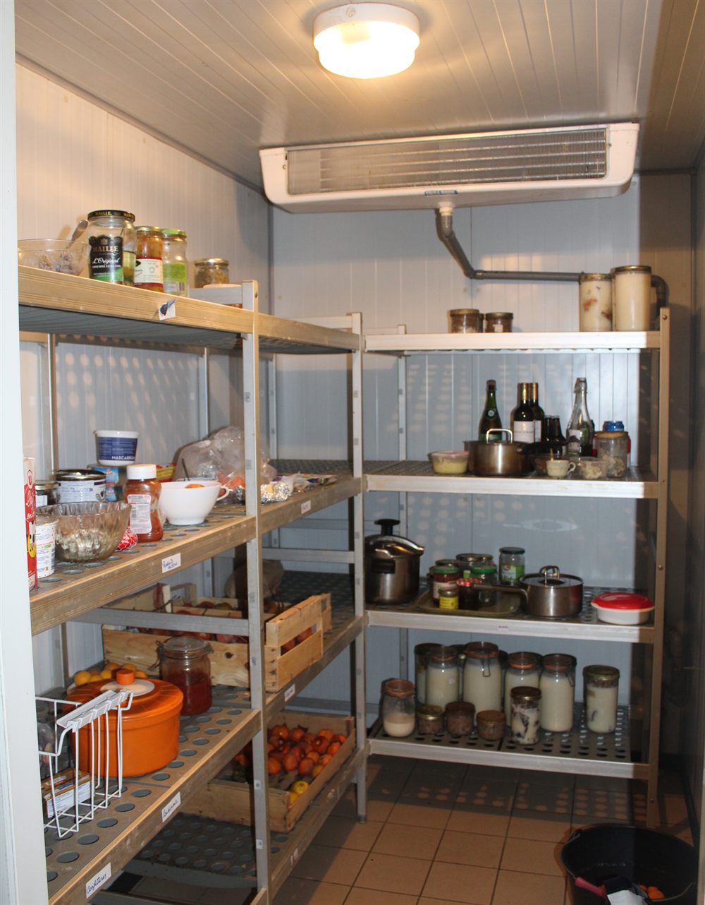 Inside one of the workshop cold rooms: aluminium shelving stacked with preserving jars and crates of fruit.